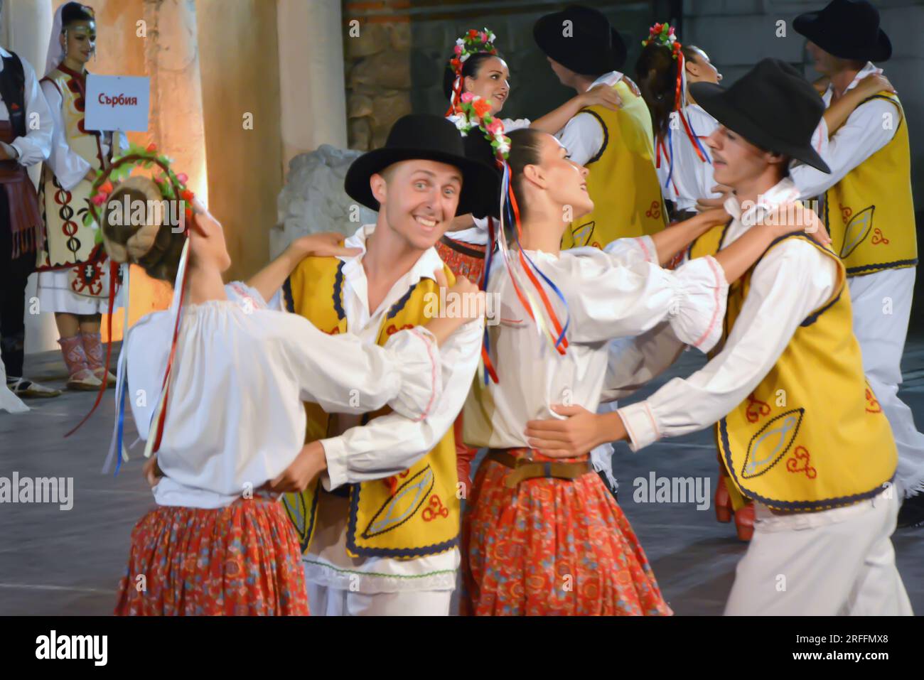 Un groupe de danseurs de la République de Serbie en costumes colorés exécutent une danse traditionnelle au XXI Festival International de folklore à anci Banque D'Images