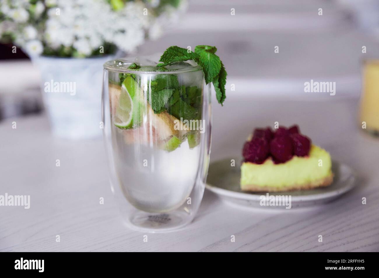 Mojito frais sans alcool et tranche de gâteau aux framboises sur la table dans le café. Nourriture d'été. Banque D'Images