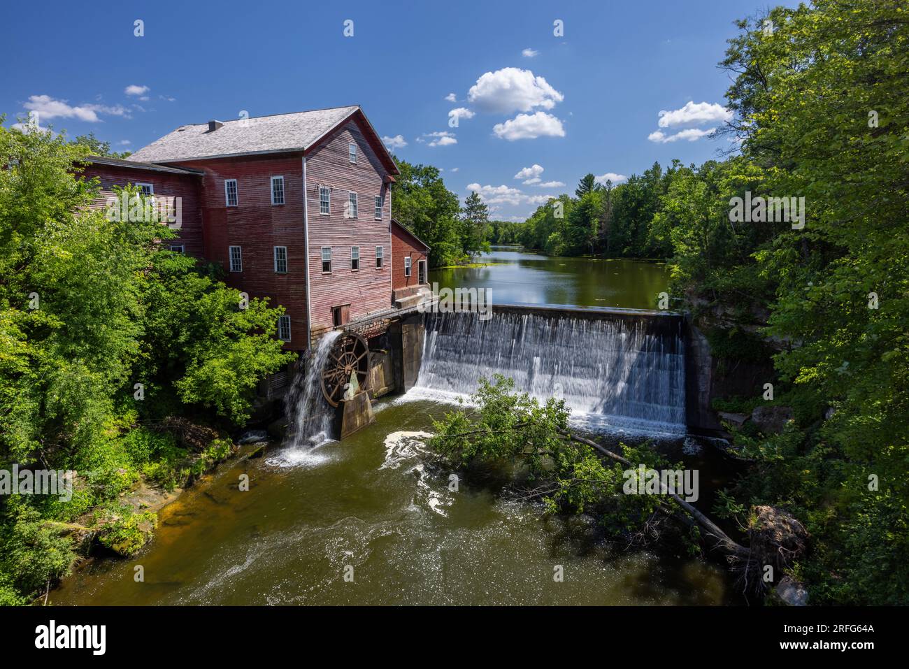 Un vieux moulin à grist rouge avec roue à eau et barrage. Banque D'Images