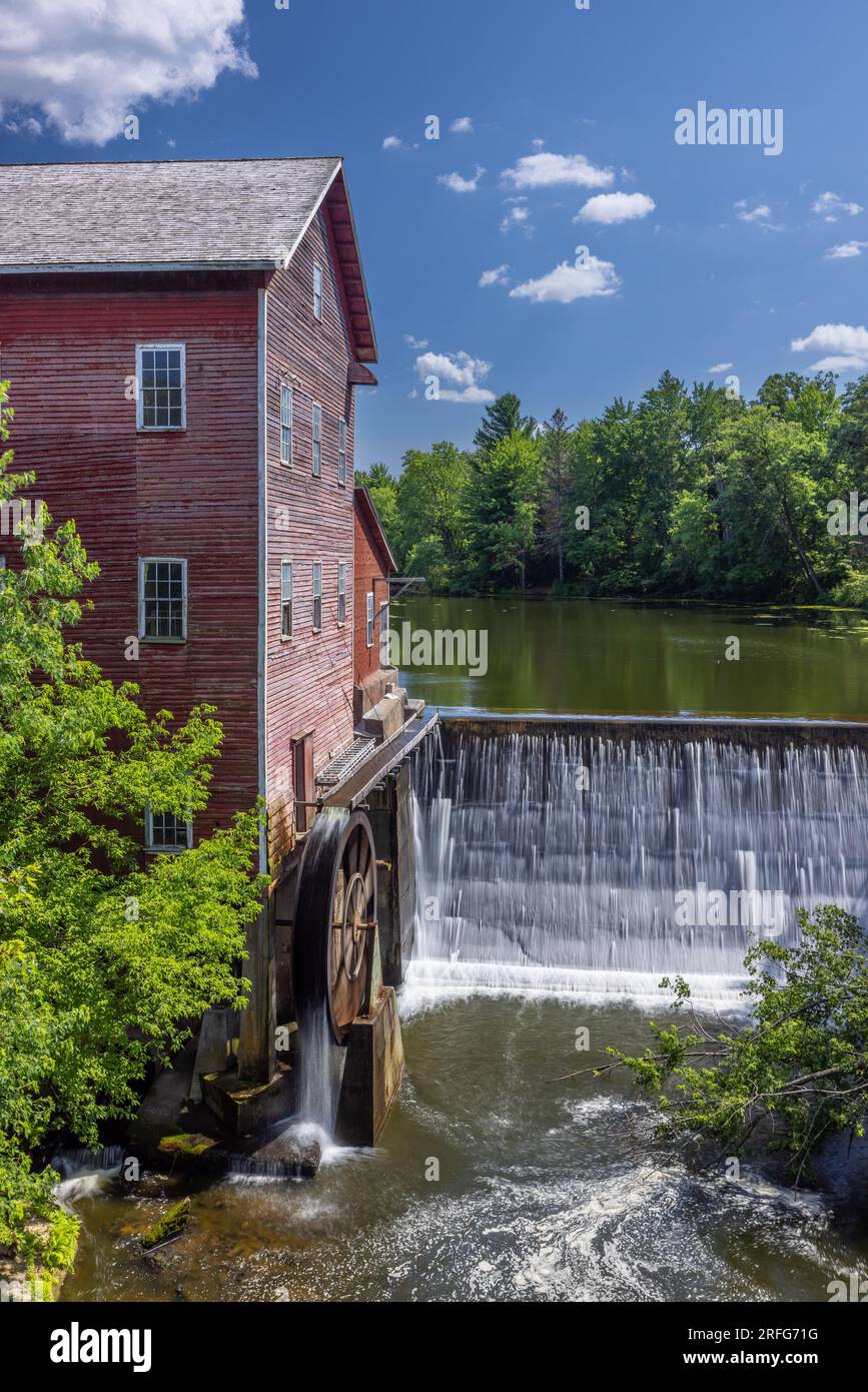 Un vieux moulin à grist rouge avec roue à eau et barrage. Banque D'Images