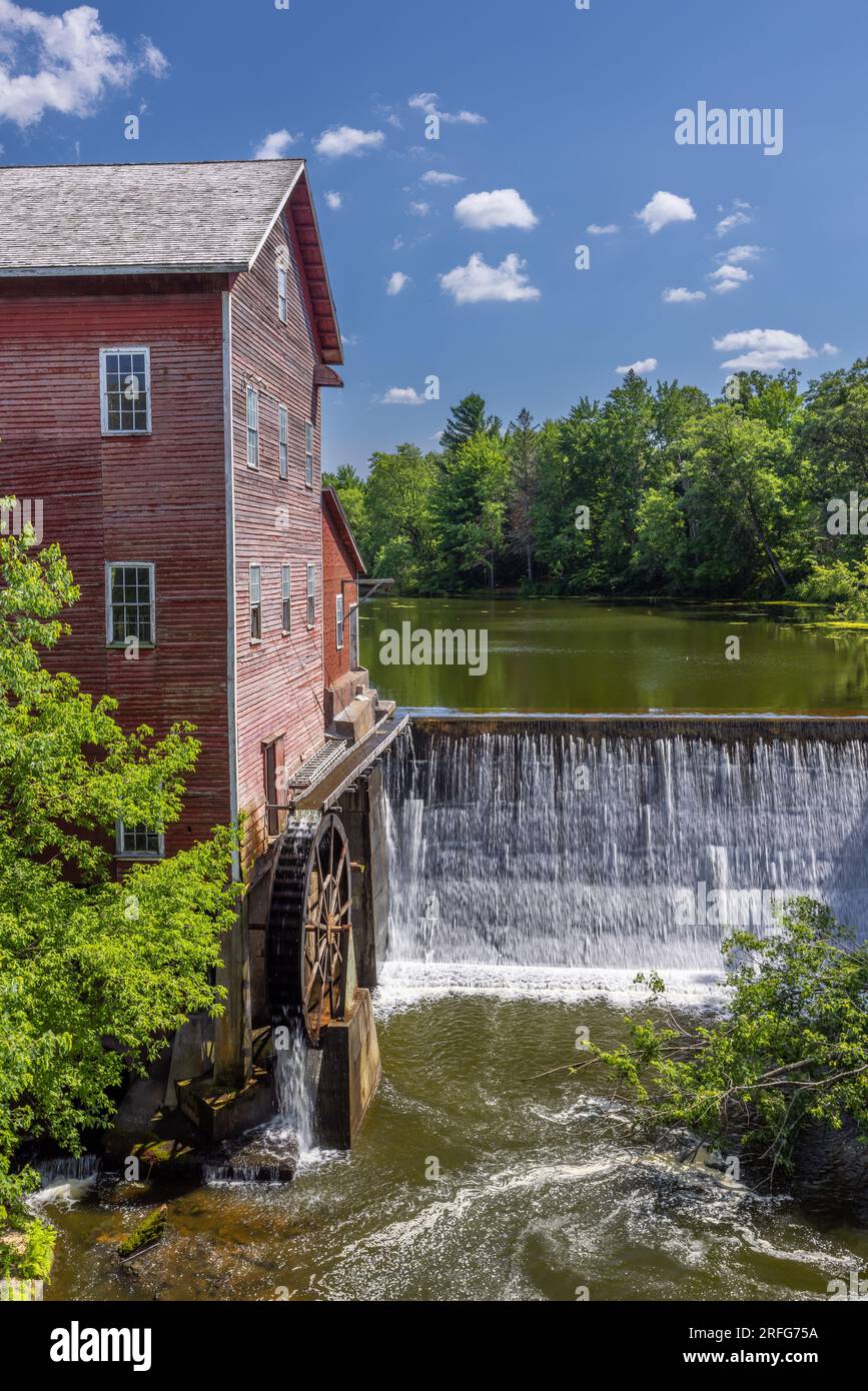 Un vieux moulin à grist rouge avec roue à eau et barrage. Banque D'Images