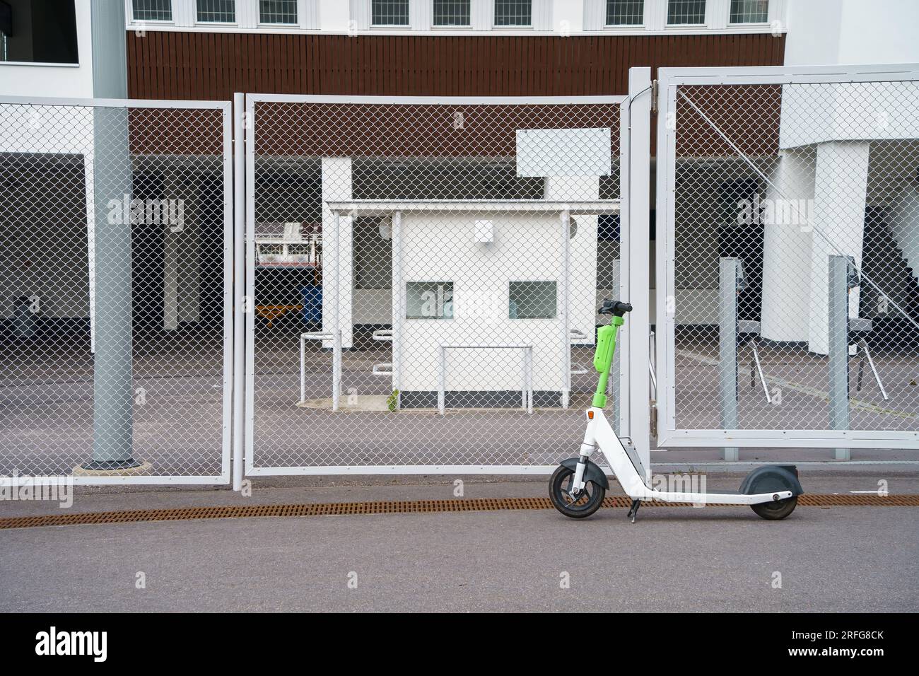 Scooter électrique stationné à l'extérieur de la clôture du stade Banque D'Images