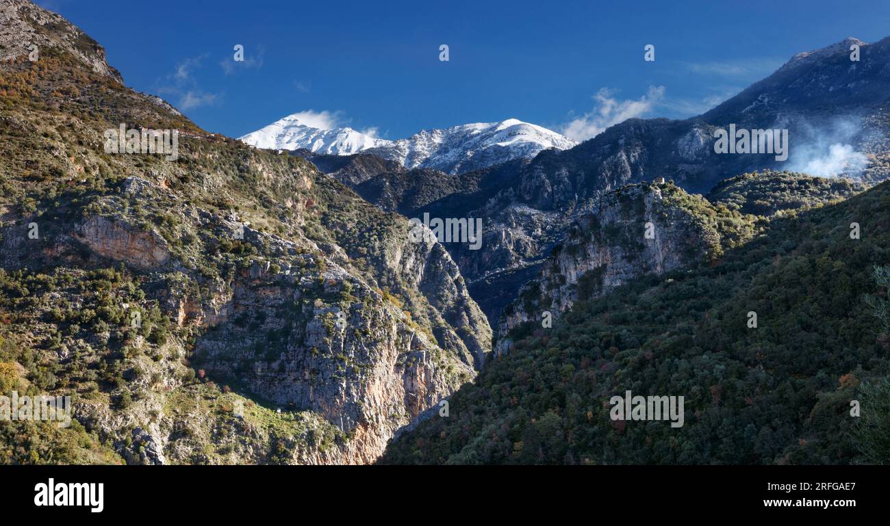 Vue le long des gorges de Vyros dans le Péloponnèse en Grèce vers le village de Tseria et le sommet enneigé de Profitis Ilias dans le mont Taygetos Banque D'Images