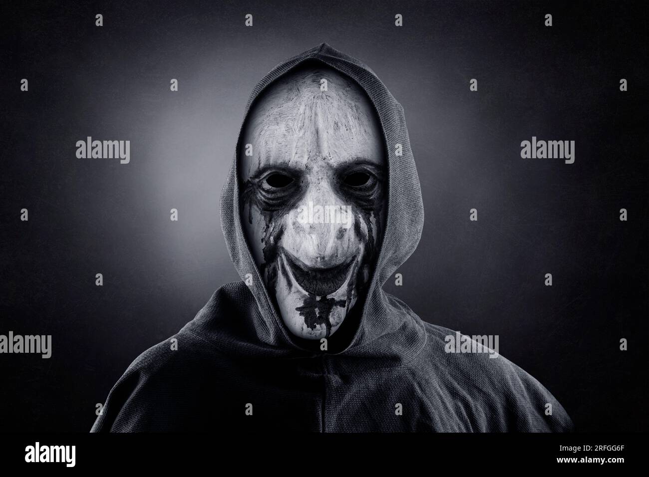 Figurine sinistre avec cape à capuchon sur fond sombre et brumeux Banque D'Images
