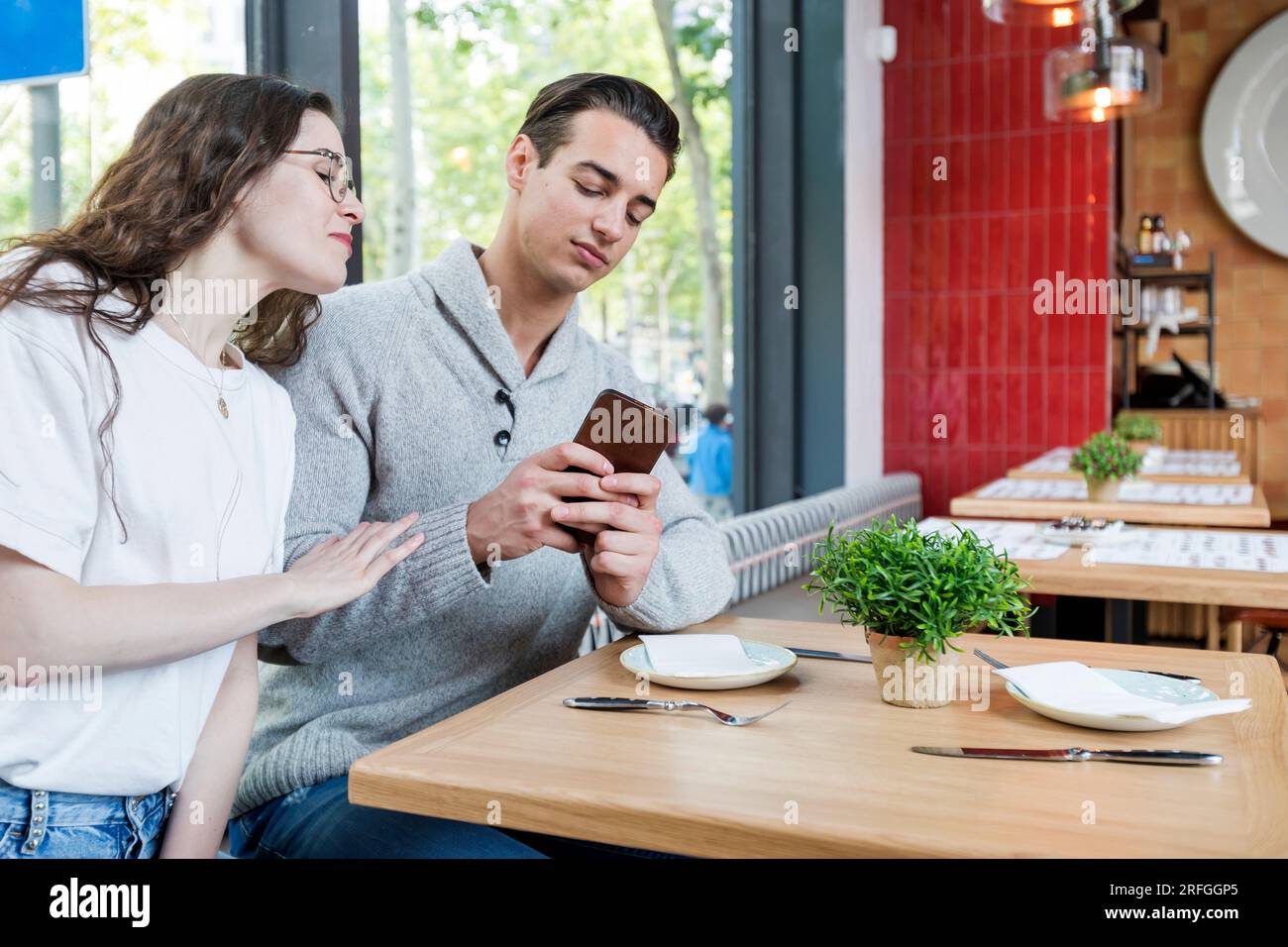 Couple heureux regardant mobile au bar de la cave - femme et homme assis dehors tout en souriant regardant smartphone - Lifestyle et concept technologique Banque D'Images