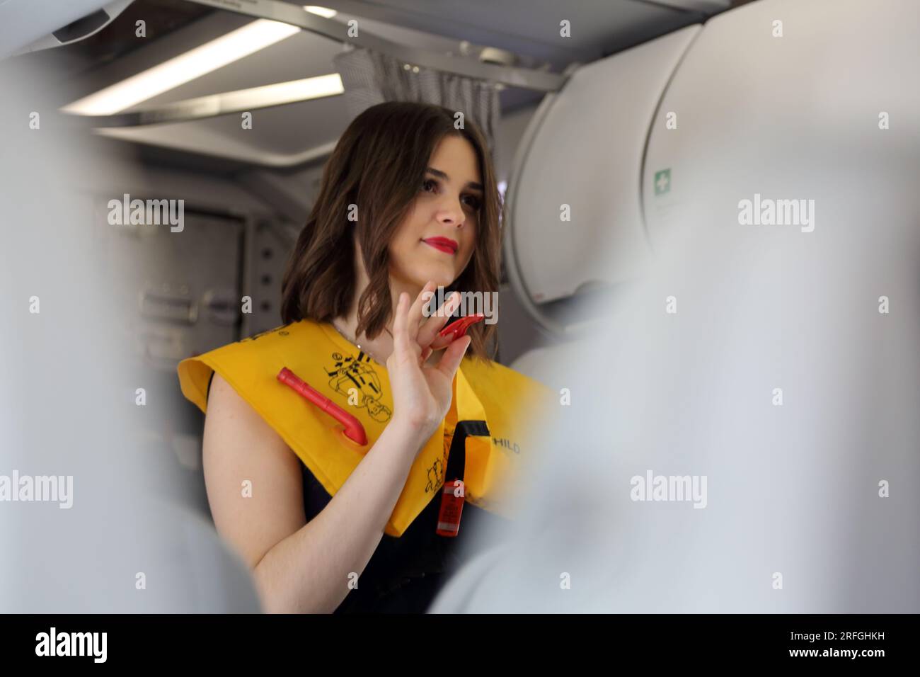 Heathrow London Airport England agent de bord démontrant les procédures de sécurité portant un gilet de sauvetage gonflable avant le vol Banque D'Images