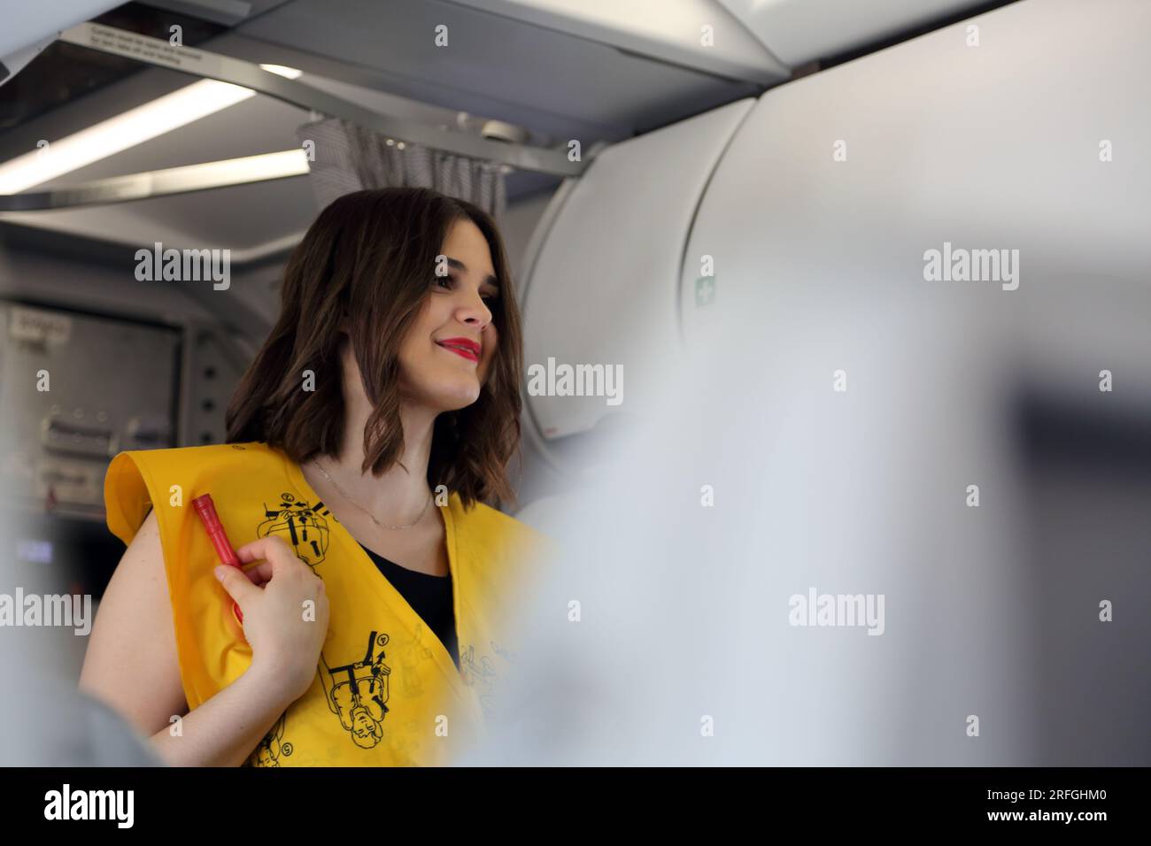 Heathrow London Airport England agent de bord démontrant les procédures de sécurité portant un gilet de sauvetage gonflable avant le vol Banque D'Images