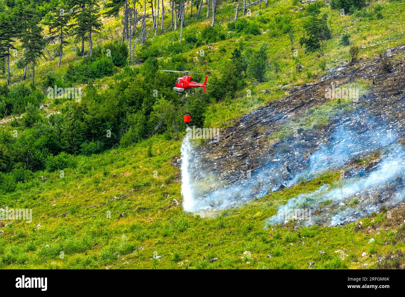 Scène dramatique avec flammes et fumée d'un feu de forêt. Protection civile hélicoptère combat les flammes avec de l'eau Monte Morrone, Parc National Maiella Banque D'Images