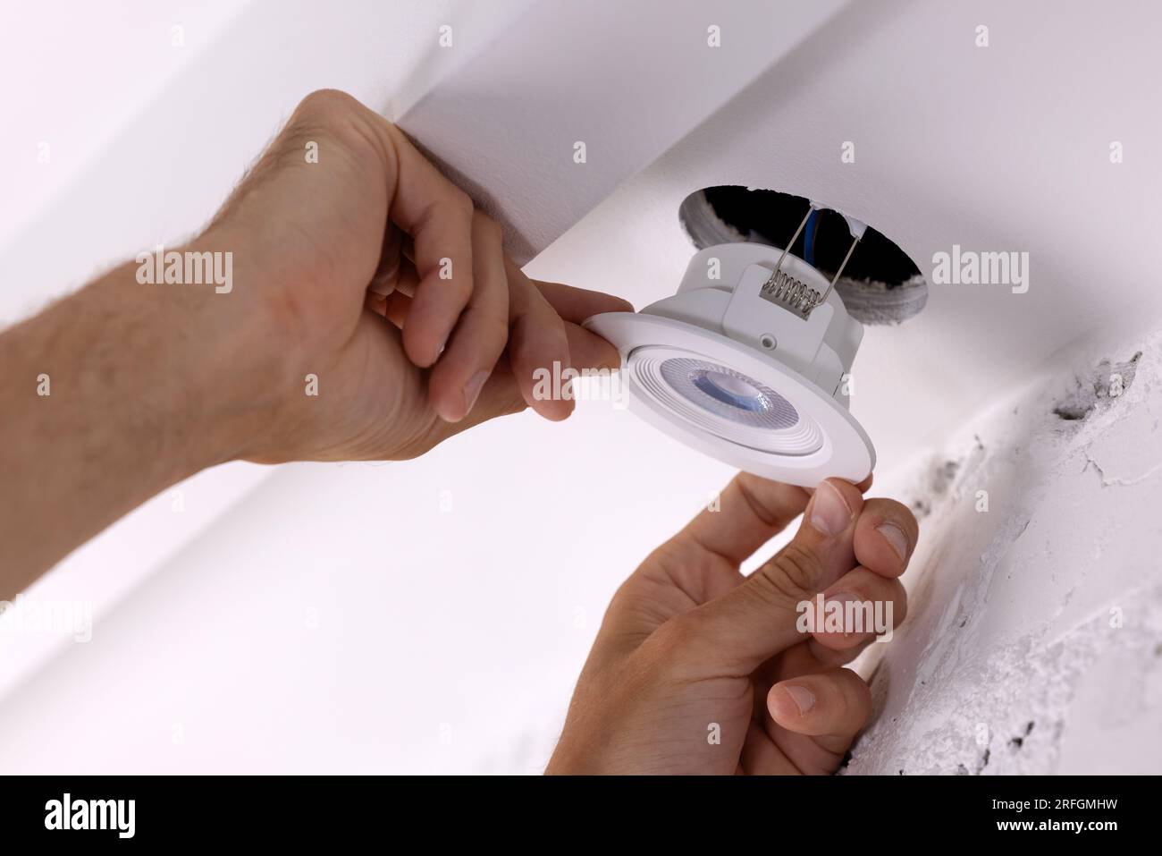électricien insère la lampe encastrée dans le trou de plafond de cloison sèche. éclairage led domestique Banque D'Images