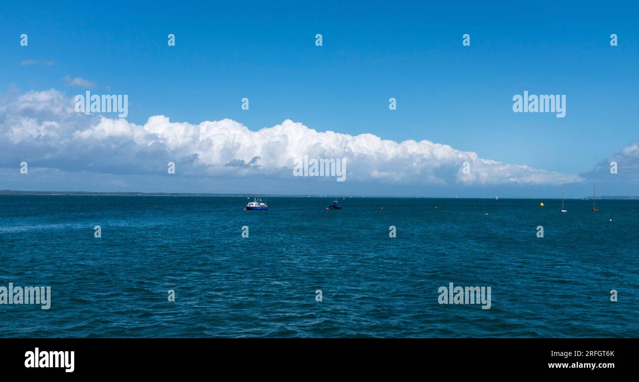 Des nuages blancs se sont réunis le long de l'horizon à Yarmouth, île de Wight, Angleterre, Royaume-Uni contrastant avec la mer bleue riche. Banque D'Images