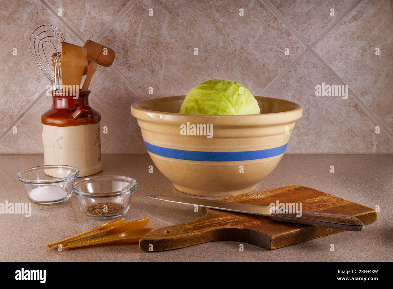 Une tête pleine de chou vert sur le point d'être coupée et combinée avec du sel et des graines de carvi pour préparer un grand bol de choucroute juste à temps pour Octoberfest Banque D'Images