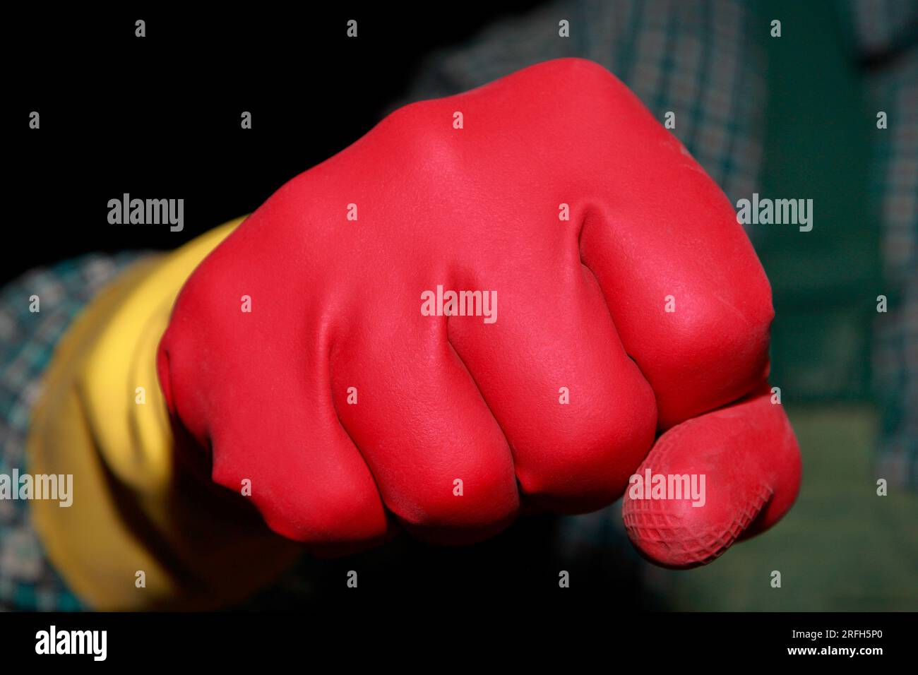 Le poing de l'homme dans les gants en caoutchouc rouge montre la force et la conduite. Sa poignée prête à maîtriser le travail de nettoyage à venir. Banque D'Images