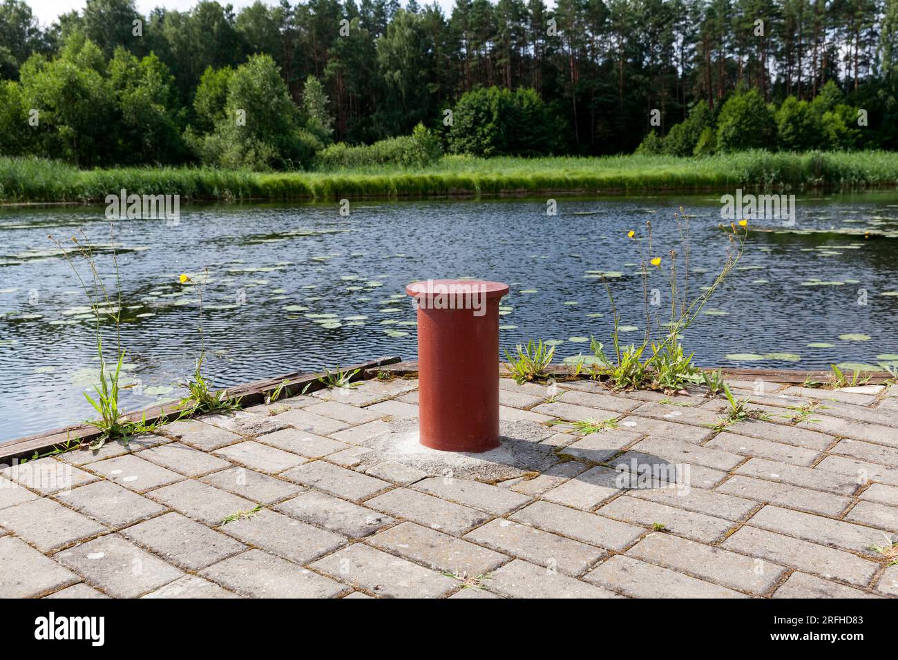 Fixation métallique pour amarrer les bateaux et les navires à la jetée près du lac, un poteau métallique rouge (Bollards) pour attirer l'attention Banque D'Images