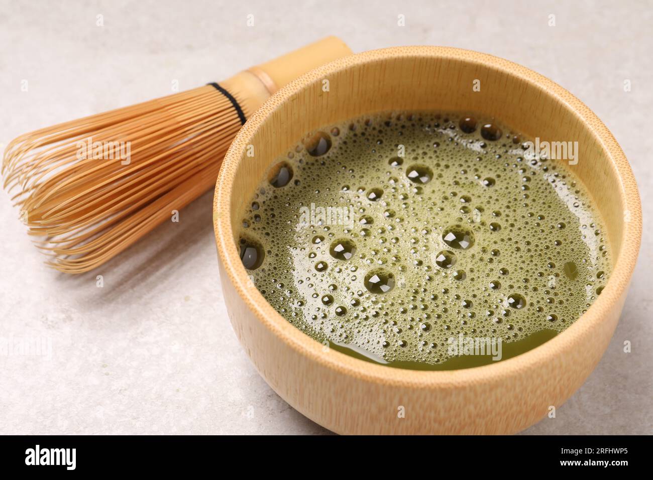 Bol de thé matcha frais et fouet en bambou sur la table lumineuse, gros plan Banque D'Images