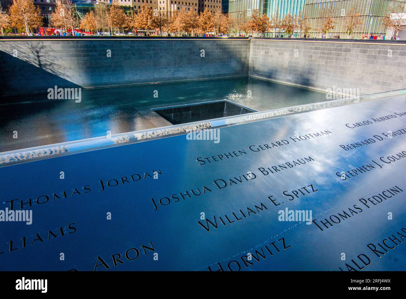 Clloseup photos des noms des victimes des attentats terroristes du 9/11 septembre sur le site commémoratif du 11 9/11 septembre avec des arbres en couleur d'automne en arrière-plan. Banque D'Images