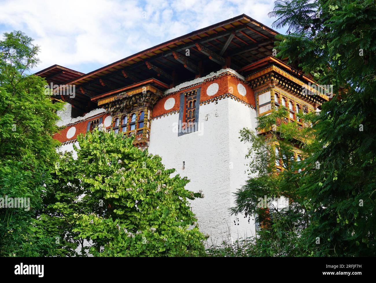 Regardant vers le haut un coin de Punakha Dzong encadré par des arbres verts feuillus dans le Royaume du Bhoutan. Construit en 1638, le dzong est le deuxième plus ancien du Bhoutan Banque D'Images