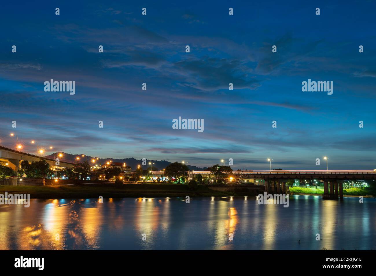 Les lampadaires et les feux de voiture coulent et se reflètent sur le lac. Scène de nuit romantique. Appréciez le ciel étoilé de la voie lactée en été à Bitan, New Taipei City. Banque D'Images