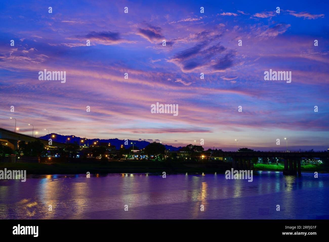 Les lampadaires et les feux de voiture coulent et se reflètent sur le lac. Scène de nuit romantique. Appréciez le ciel étoilé de la voie lactée en été à Bitan, New Taipei City. Banque D'Images