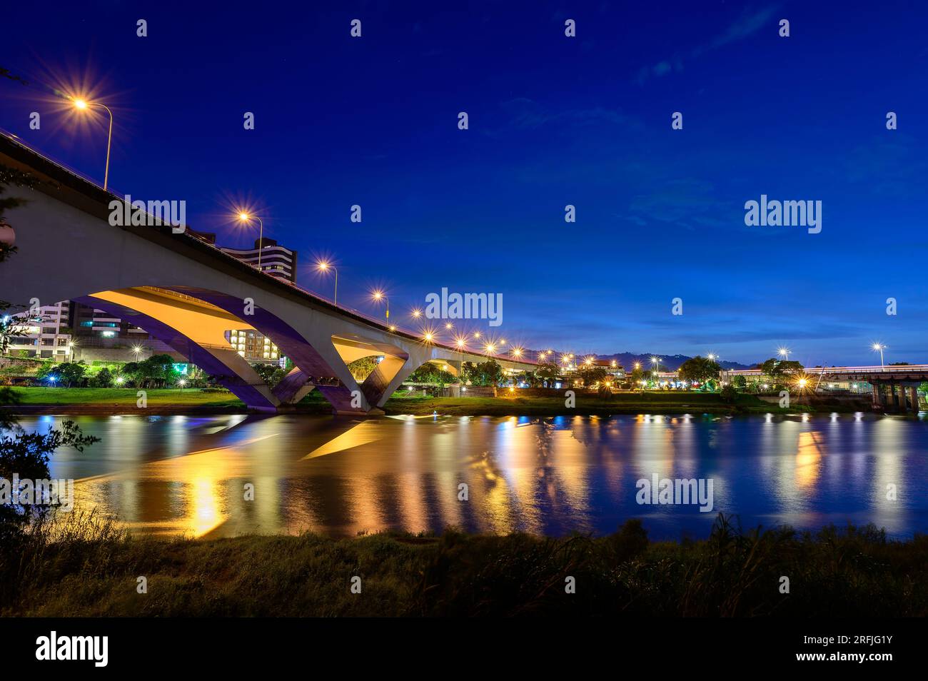 Les lampadaires et les feux de voiture coulent et se reflètent sur le lac. Scène de nuit romantique. Appréciez le ciel étoilé de la voie lactée en été à Bitan, New Taipei City. Banque D'Images