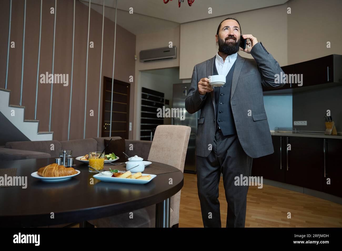 L'homme se tient à une table avec un téléphone et du café Banque D'Images
