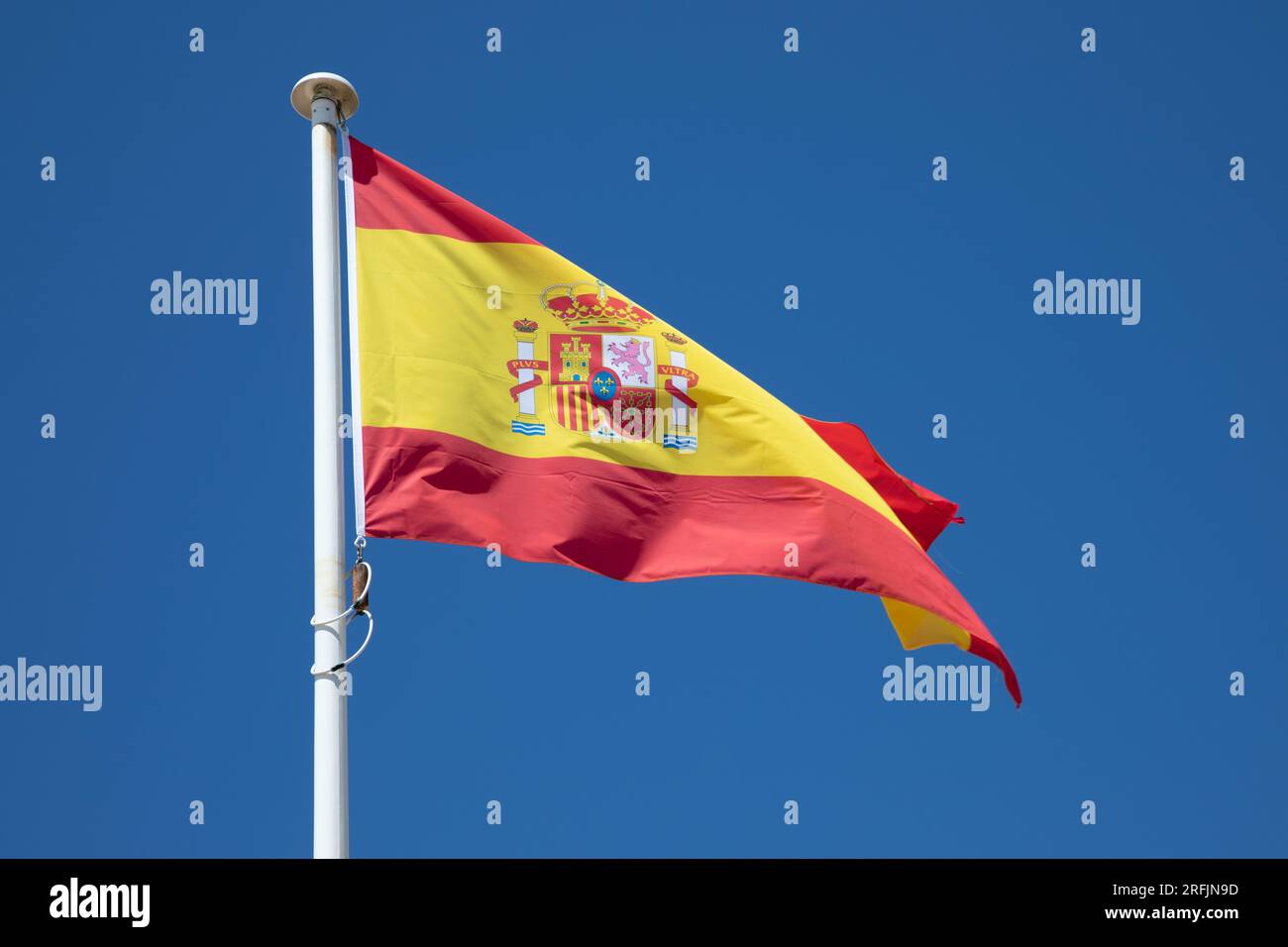 espagne drapeau national espagnol sur le dessus du mât dans le vent et le ciel bleu Banque D'Images