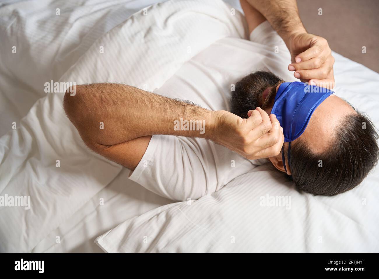 Le mâle se réveille et enlève son bandage de sommeil, il a une barbe  épaisse bien soignée Photo Stock - Alamy