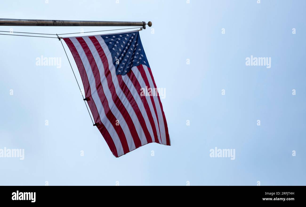 Drapeau des États-Unis d'Amérique sur un poteau agitant sur fond de ciel bleu. Symbole du signe USA Banque D'Images