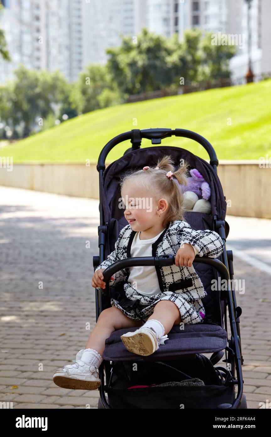 Bébé en poussette sur une promenade dans le parc d'été. Adorable petite  fille assise dans une poussette. Enfant en buggy Photo Stock - Alamy