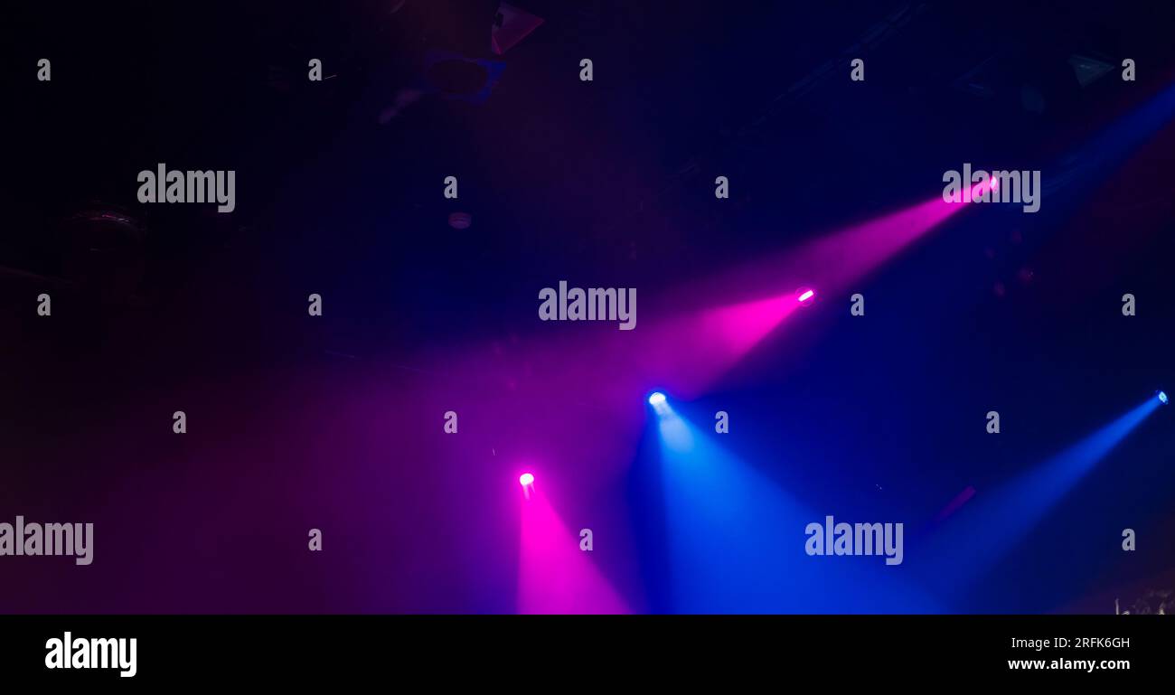 Faisceaux violets et bleus de projecteurs de scène en fumée sur fond flou foncé, équipement moderne d'éclairage de scène Banque D'Images