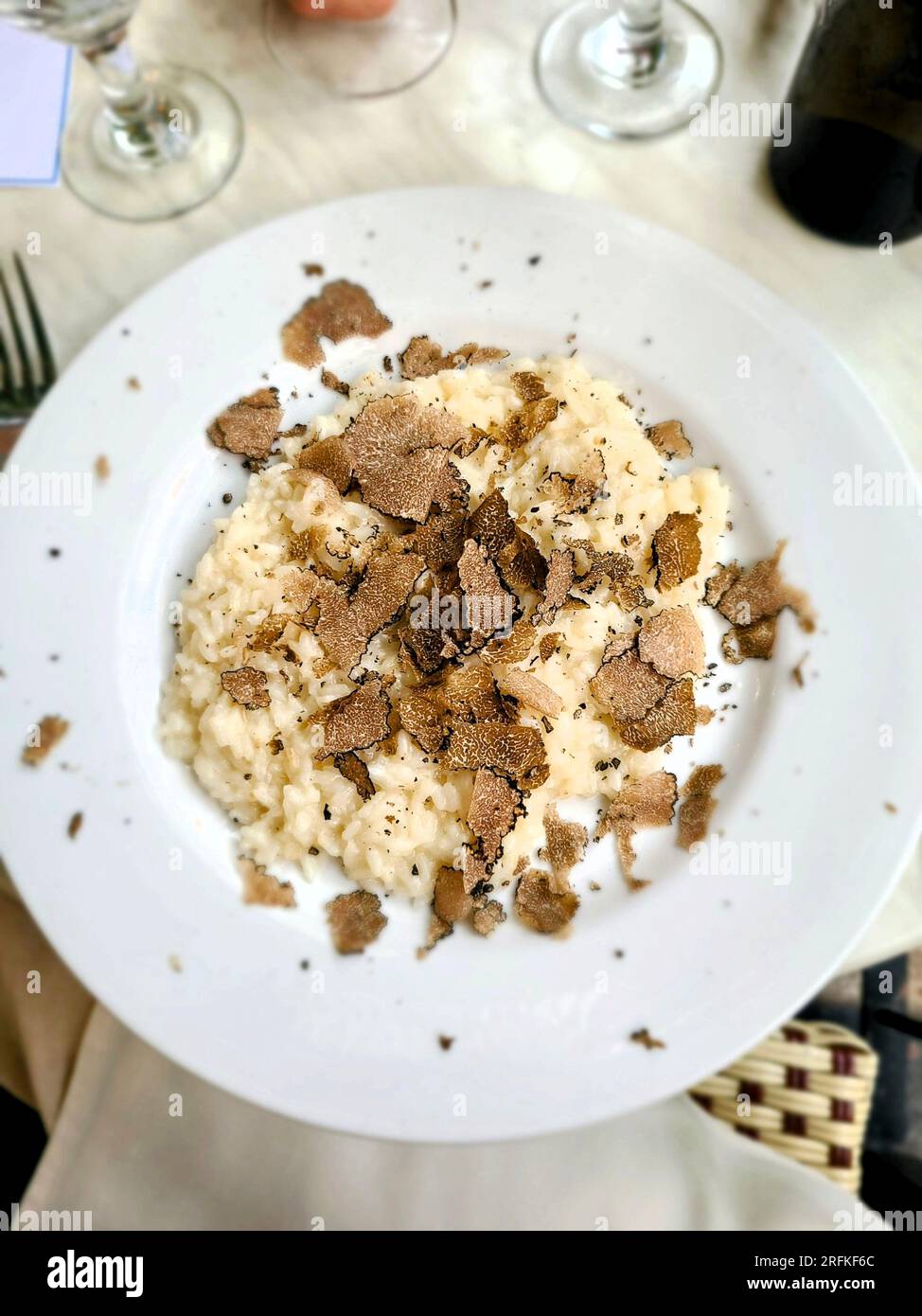 Risotto aux truffes sur une assiette blanche avec fond de table Banque D'Images