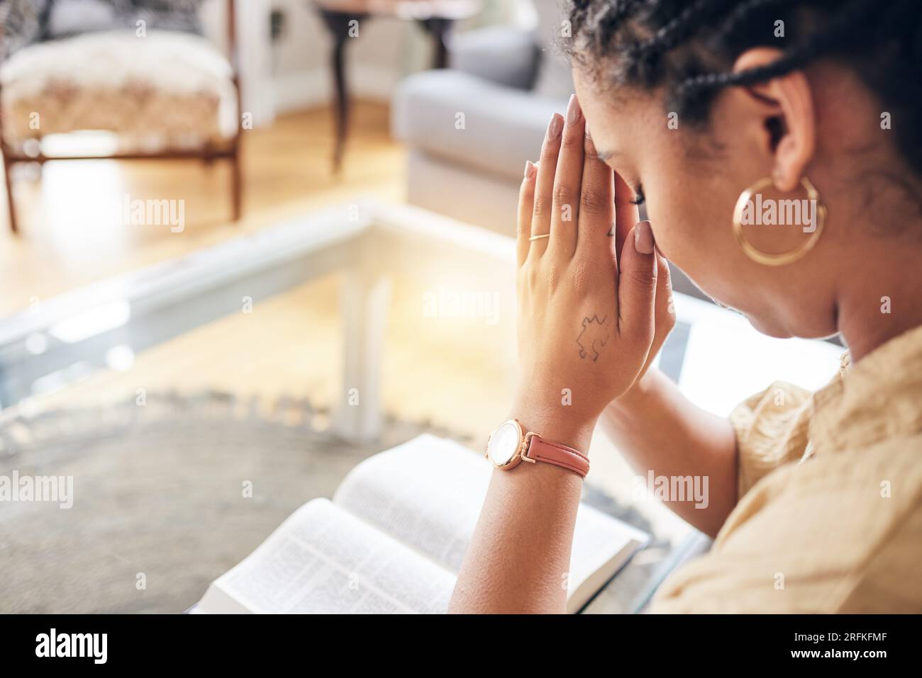 Adoration, bible et femme dans le salon priant, merci et louange, miséricorde et bénédiction à la maison. Mains, priez et dame chrétienne en prière à Dieu Banque D'Images
