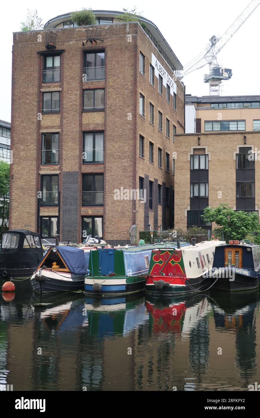 La vie sur l'eau : bateaux étroits amarrés à Battlebridge Basin sur le Regent's Canal à côté des appartements londoniens et de l'ancien Albert Dock. Banque D'Images