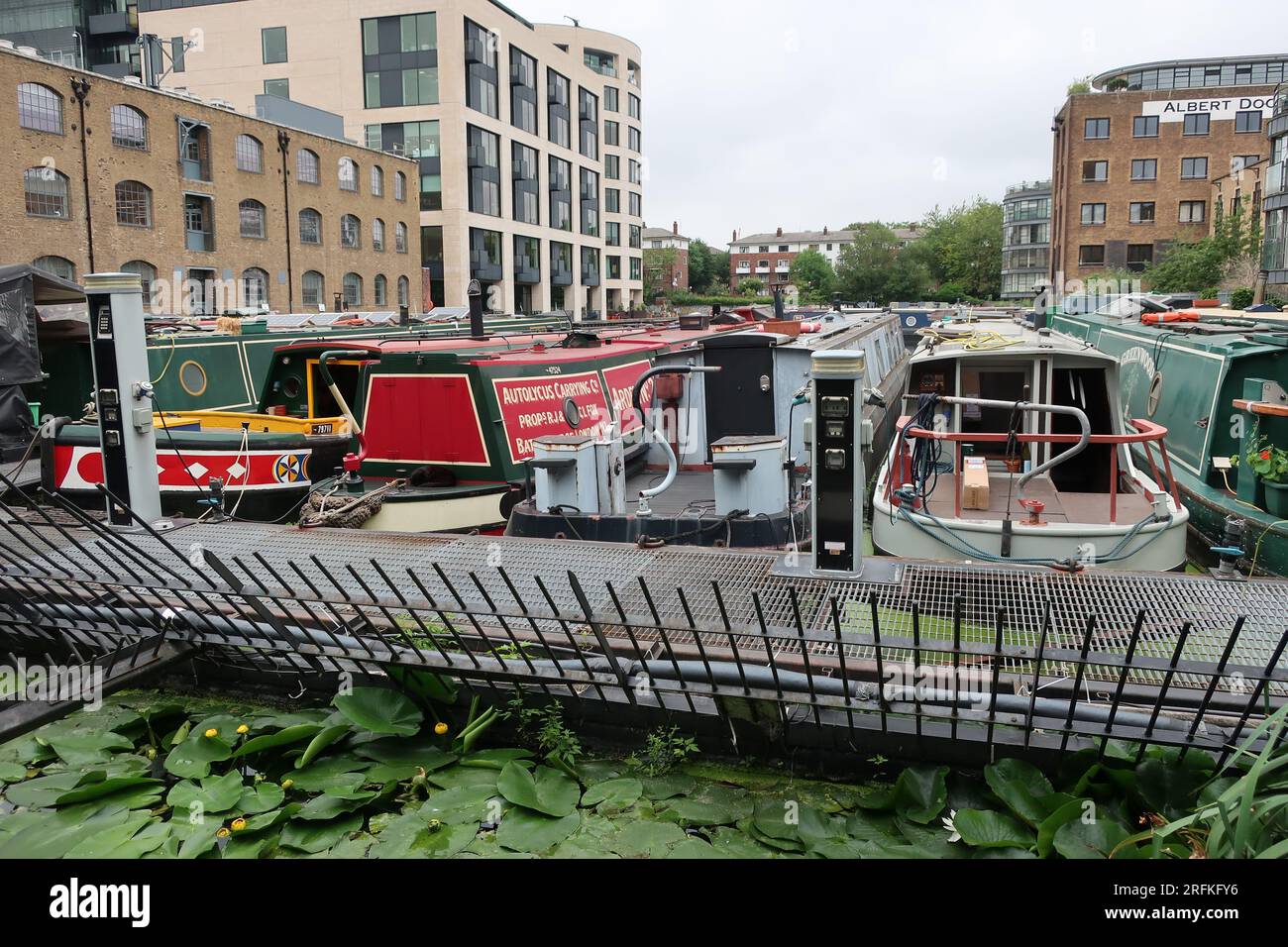La vie sur l'eau : bateaux étroits amarrés à Battlebridge Basin sur le Regent's Canal à côté des appartements londoniens et de l'ancien Albert Dock. Banque D'Images