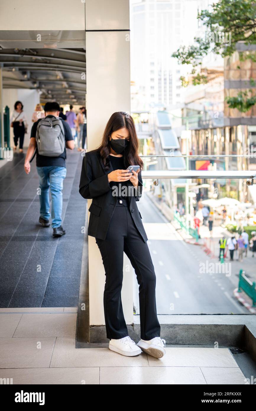 Une jeune fille thaïlandaise prend un moment pour vérifier son téléphone à Chong Nonsi BTS Sky train station Bangkok, Thaïlande. Banque D'Images