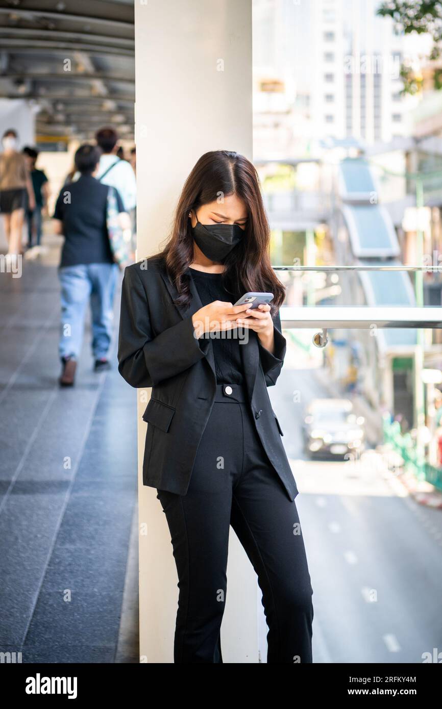 Une jeune fille thaïlandaise prend un moment pour vérifier son téléphone à Chong Nonsi BTS Sky train station Bangkok, Thaïlande. Banque D'Images