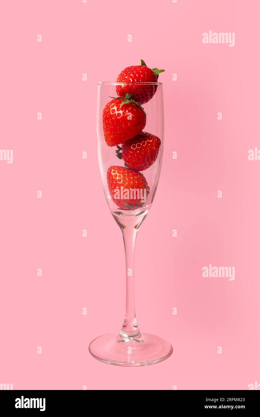 Un verre plein de fraises mûres rouges isolé sur un fond rose. Boissons estivales. Cocktail d'été. Boissons aux fruits saines. Sweet Natural pour femme Banque D'Images