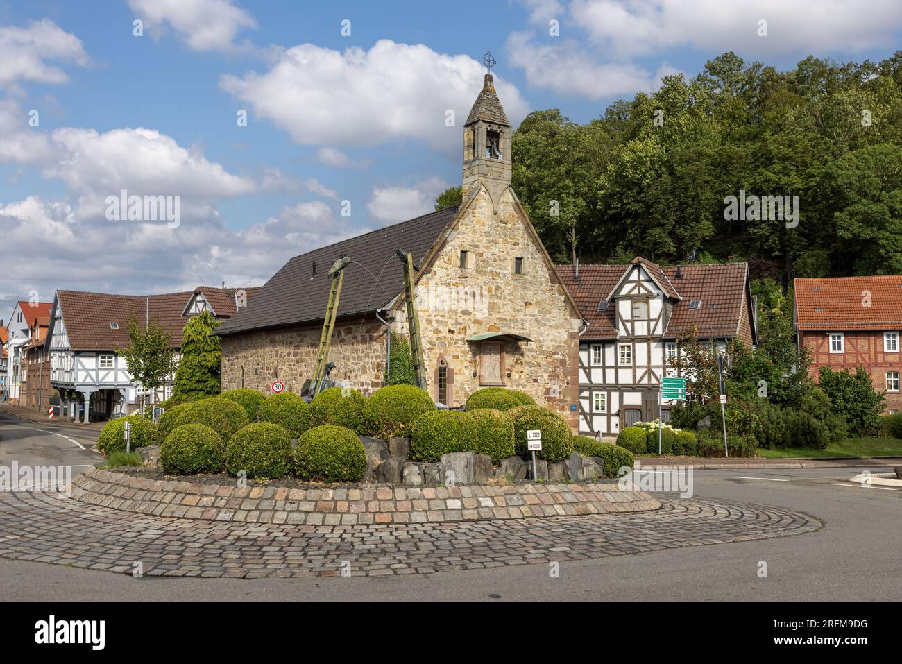 Chapelle de l'hôpital du Saint-Esprit et sculpture de fontaine 'Der Brunnen der Verwunschenn' par Carin Grudda sur le rond-point dans la ville de Gudensberg, Allemagne Banque D'Images
