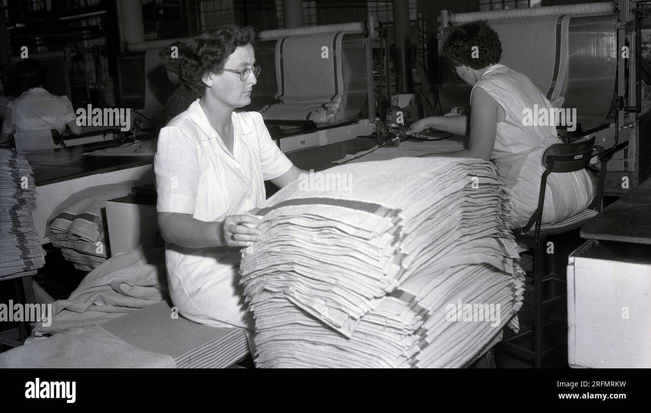 Années 1950, historique, une dame triant une pile de nouveaux tapis de bain en coton, ayant été coupés et finis par d'autres travailleuses dans une usine textile, USA. Banque D'Images