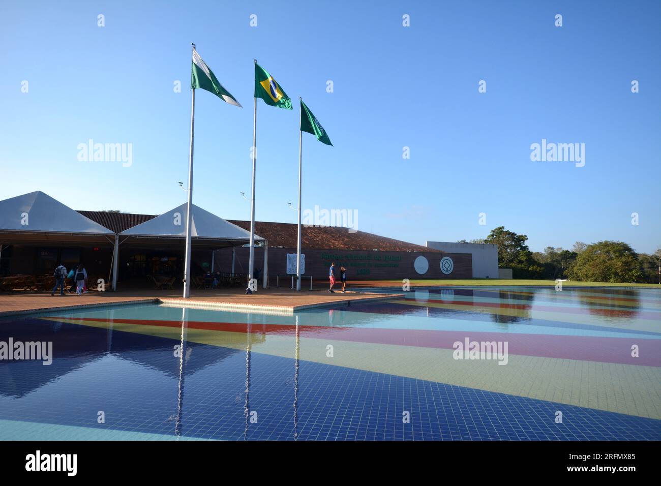Parc avec un lac en face de l'entrée des chutes d'Iguazu, considéré comme un site du patrimoine mondial national, avec drapeaux et touristes Banque D'Images