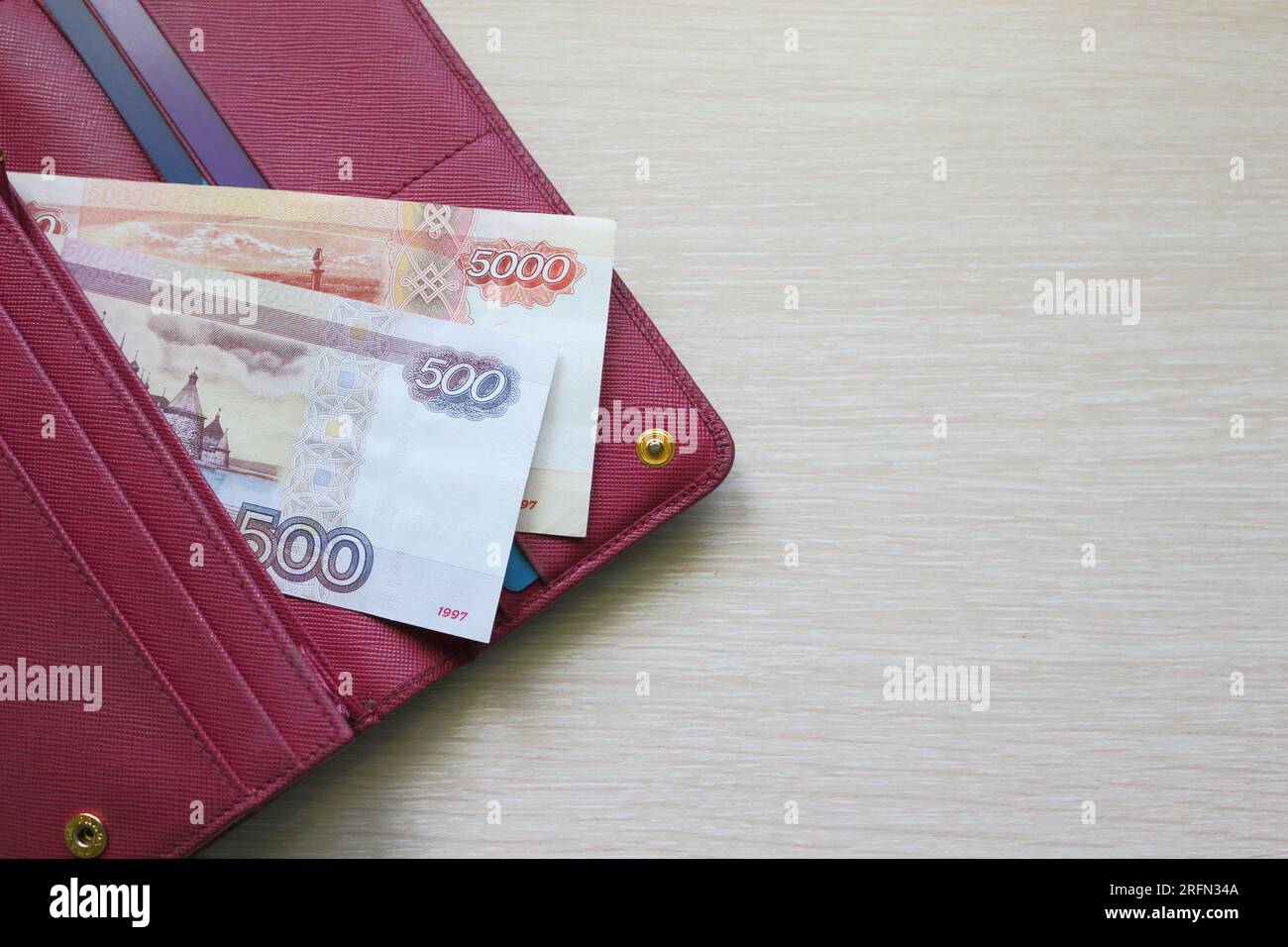 Billets de roubles russes dans un portefeuille en cuir. Portefeuille rouge Fucsia, sac à main. Fond en bois. Billets de banque Banque D'Images