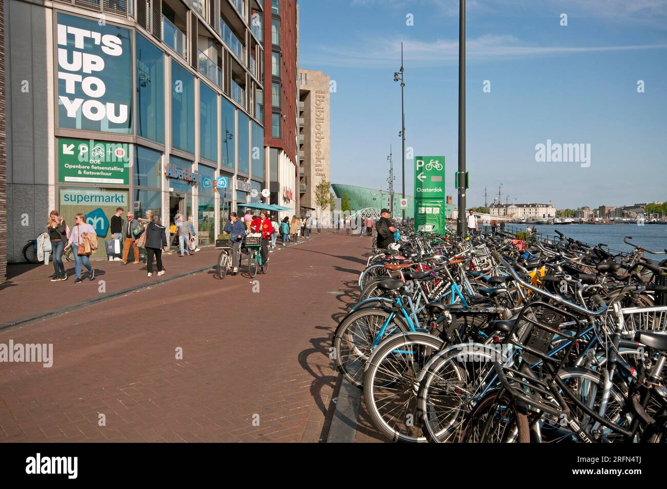 Les gens marchent et font du vélo à Oosterdokskade (en arrière-plan le Musée des Sciences Nemo), Amsterdam, pays-Bas Banque D'Images