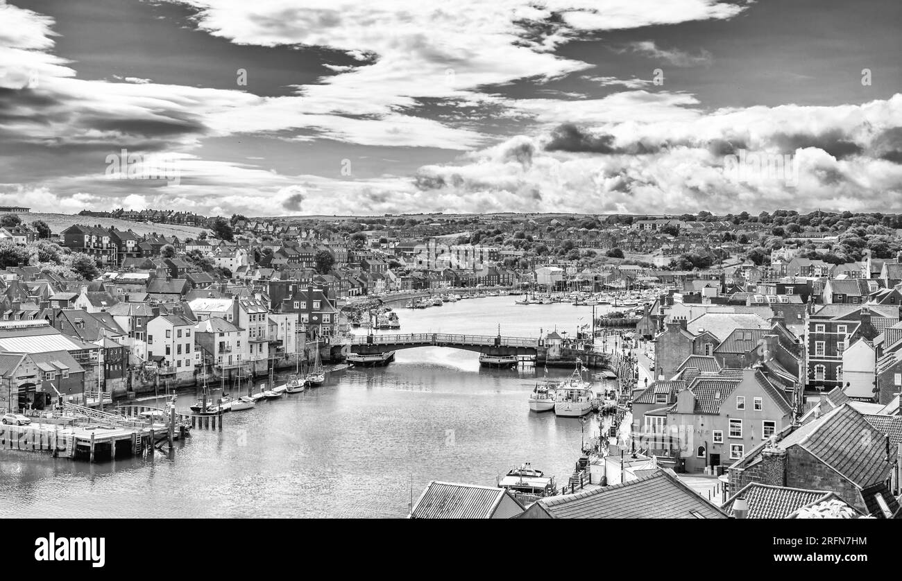 Port de Whitby et ville donnant vers l'intérieur. Les bâtiments de la ville se regroupent autour du port et un pont s'étend sur l'eau. Un ciel nuageux est au-dessus. Banque D'Images