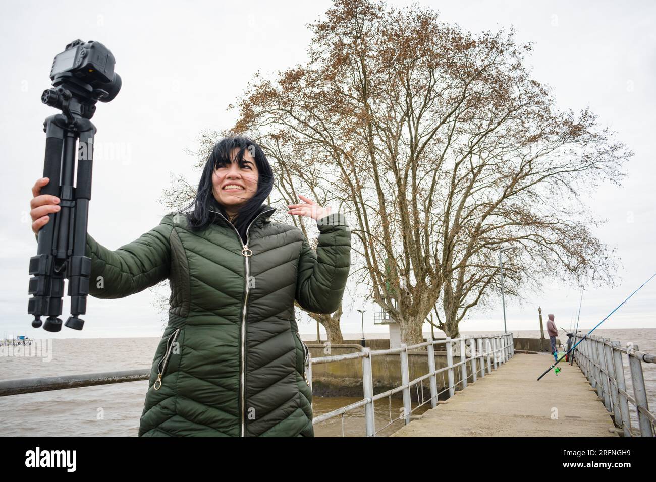 jeune vlogger vlogger vénézuélienne, souriant tenant sa caméra faisant une vidéo expliquant et parlant, debout sur une jetée du port d'olivos en bu Banque D'Images