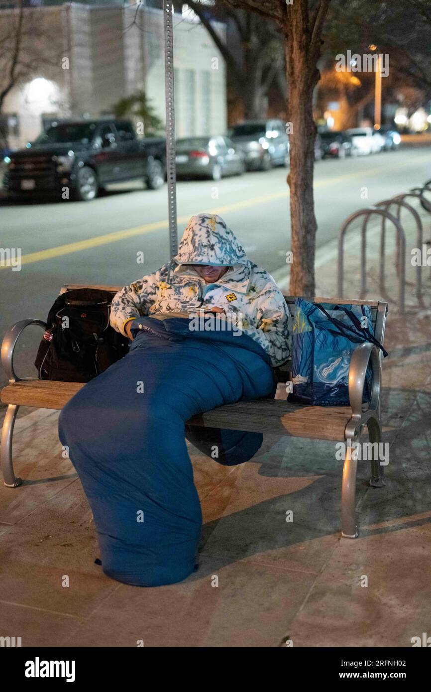 Un homme qui vit dans la rue regarde un téléphone portable alors qu'il essaie de garder au chaud dans le centre-ville d'Austin par une nuit froide de janvier dans le centre du Texas. ©Bob Daemmrich Banque D'Images
