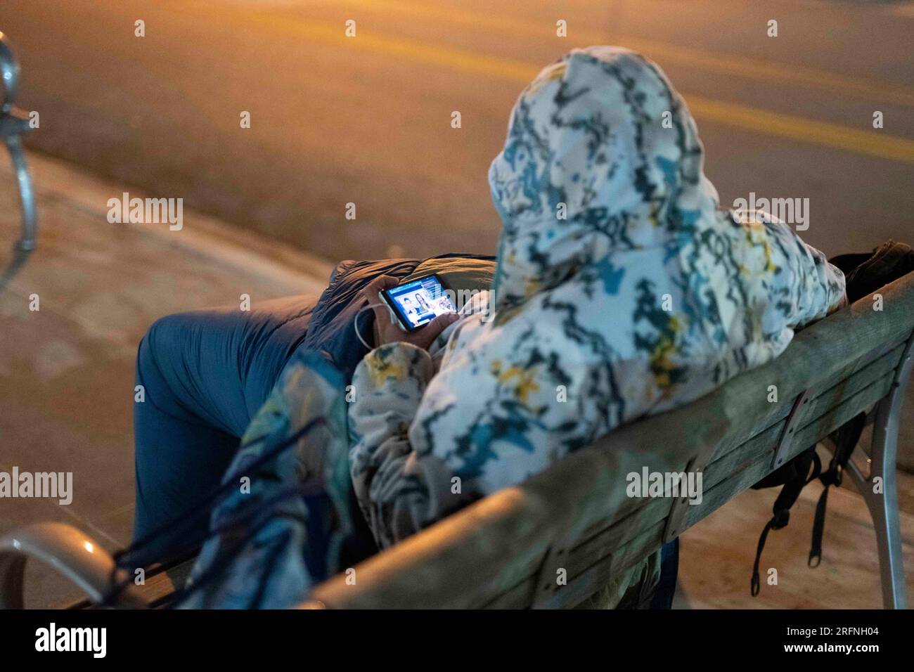 Un homme qui vit dans la rue regarde un téléphone portable alors qu'il essaie de garder au chaud dans le centre-ville d'Austin par une nuit froide de janvier dans le centre du Texas. ©Bob Daemmrich Banque D'Images