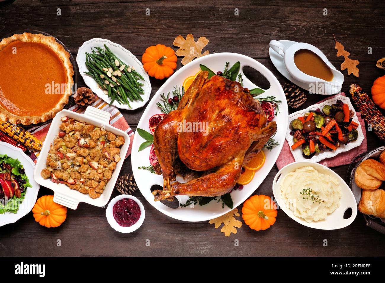 Dîner traditionnel à la dinde de Thanksgiving. Scène de table vue aérienne sur un fond de bois sombre. Dinde, purée de pommes de terre, farce, tarte à la citrouille et accompagnements. Banque D'Images