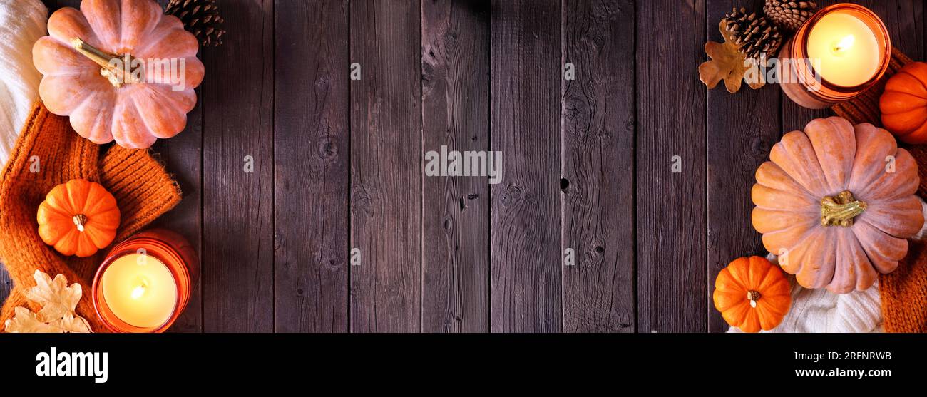Confortable double bordure d'automne avec citrouilles, chandails et bougies. Vue ci-dessus sur un fond de bannière en bois sombre. Banque D'Images