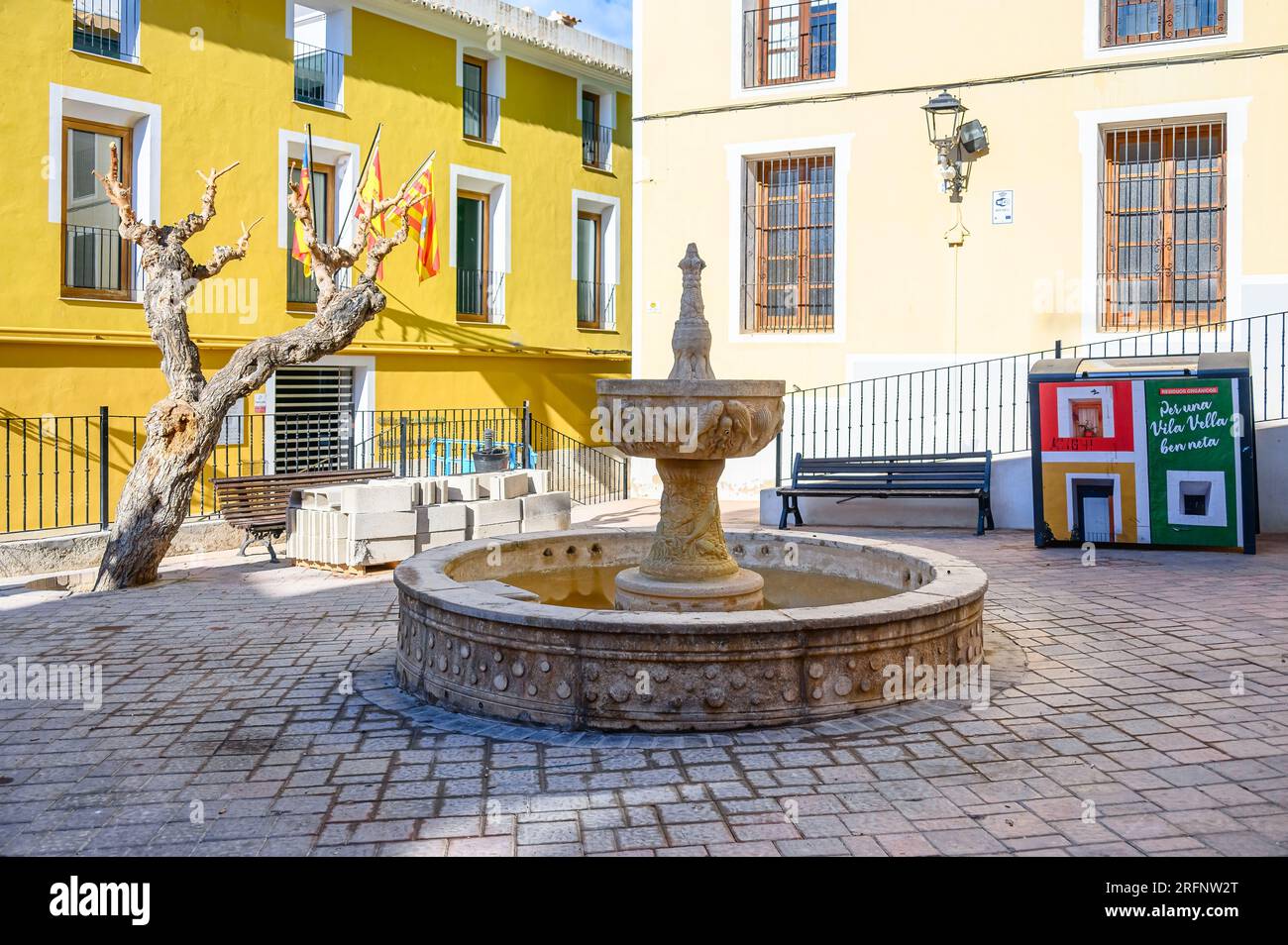 Villajoyosa, Espagne, Fontaine médiévale en pierre au centre d'un petit parkette. Le sol de la place est en pavés. Banque D'Images