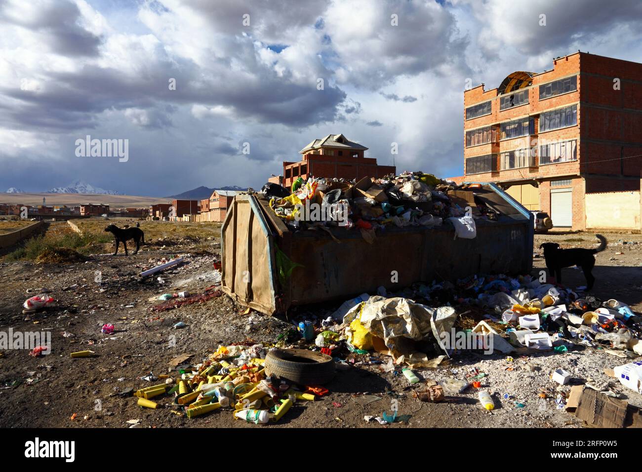Benne à ordures débordante et maison en brique à côté de Rio Seco dans la banlieue d'El Alto, altiplano et Mt Huayna Potosí en arrière-plan, Bolivie Banque D'Images