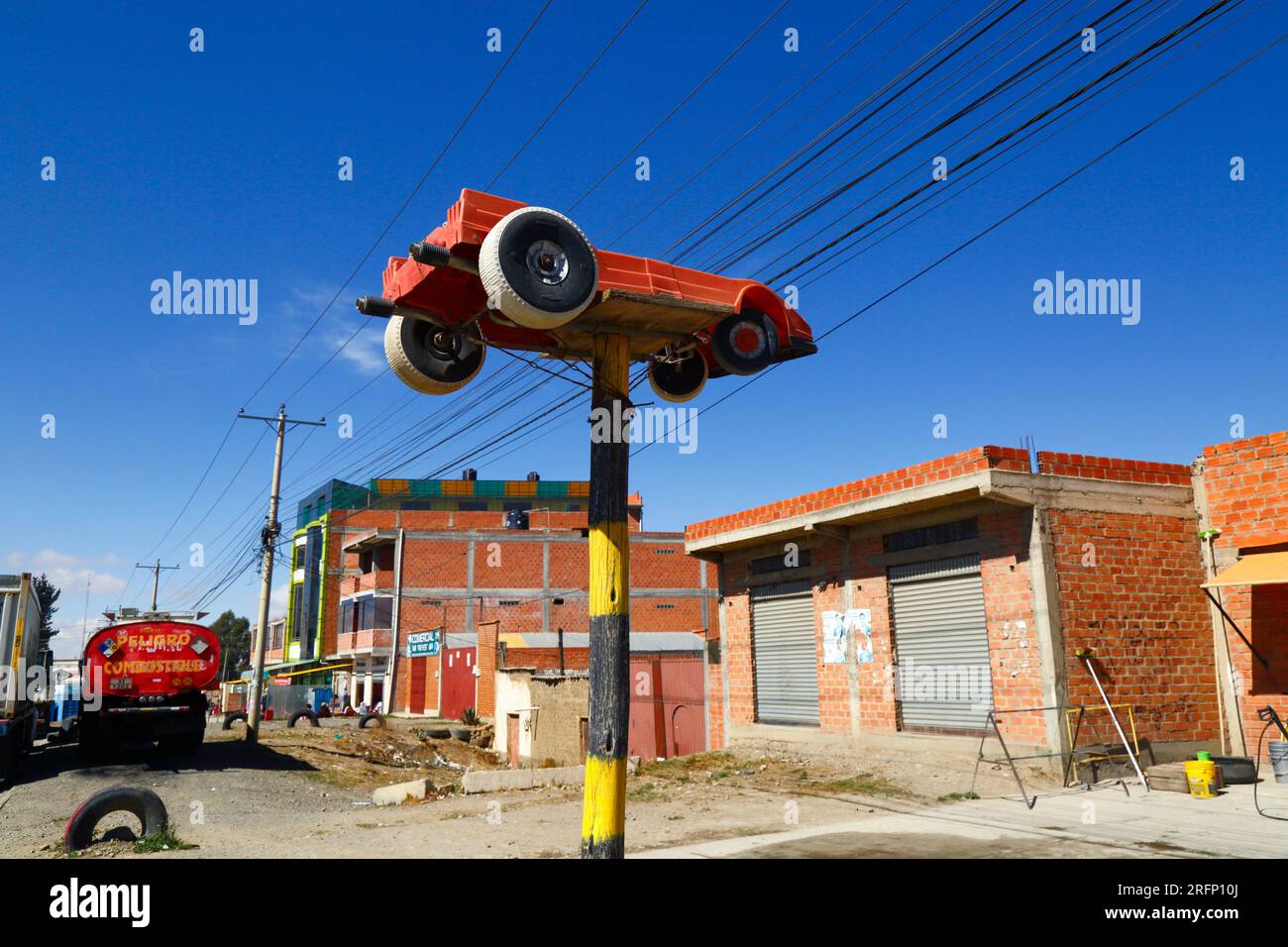 Grande voiture jouet en plastique sur poteau en bois peint en dehors de l'entreprise de lavage de voiture à côté de la route principale, El Alto, Bolivie Banque D'Images